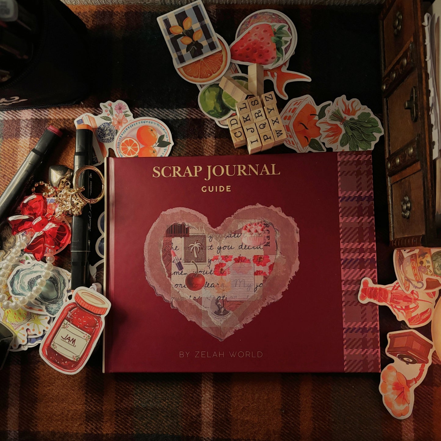 Scrap Journal Guide surrounded by pens, stickers, and ephemera in a cozy creative flat lay